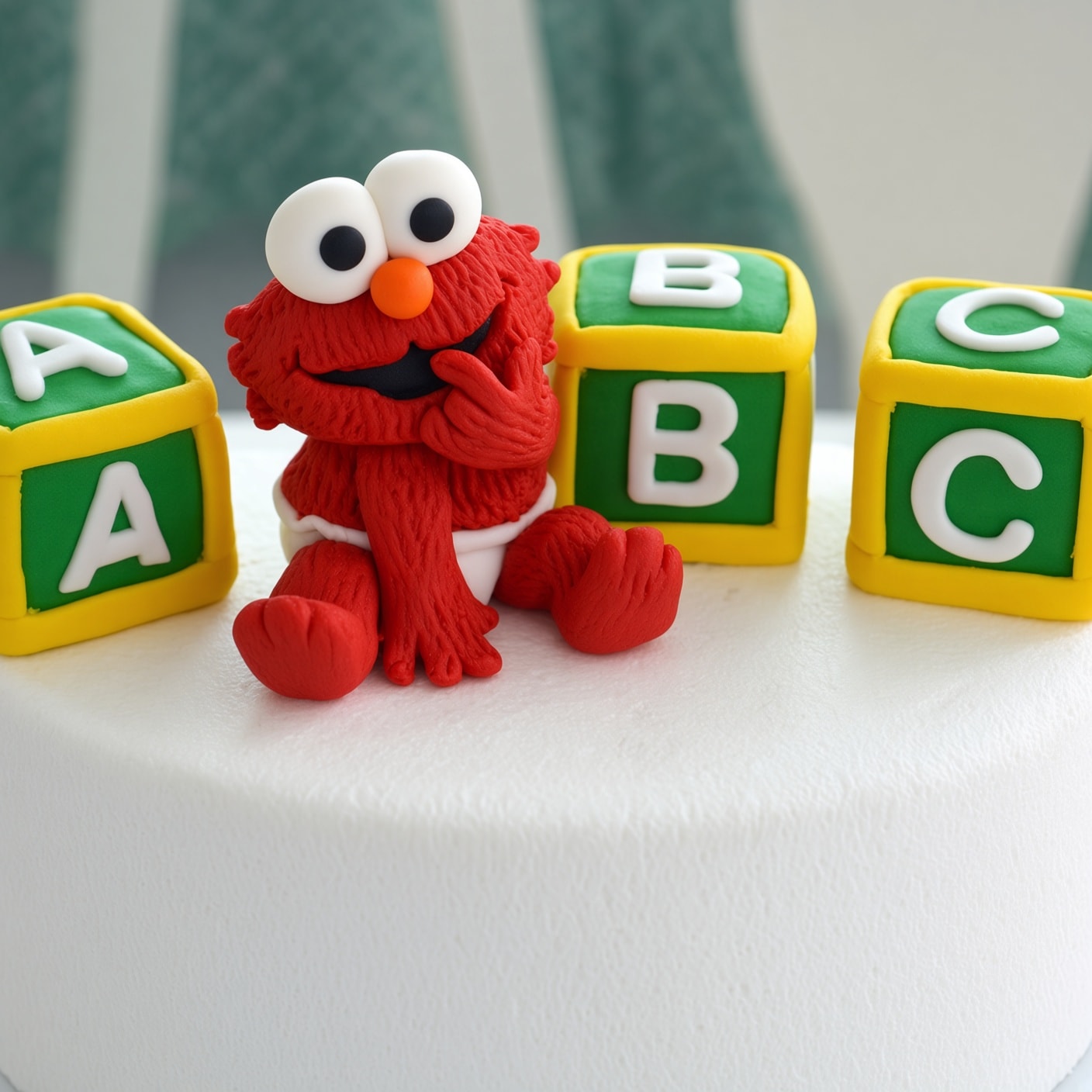 Edible Baby Elmo cake topper seated between green-and-yellow alphabet blocks on a white cake.